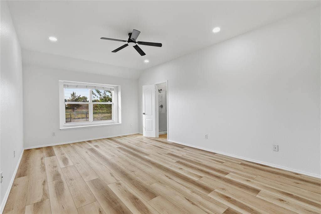 10709 Nantucket Drive, Rowlett, TX 75089 Spacious room featuring wood-finish flooring, a large window, a ceiling fan with integrated lighting, and recessed ceiling lights