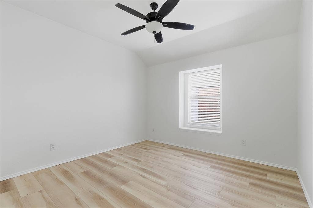 10709 Nantucket Drive, Rowlett, TX 75089 Light wood-finish flooring with white walls and trim, featuring a recessed window with blinds and a ceiling fan with integrated lighting