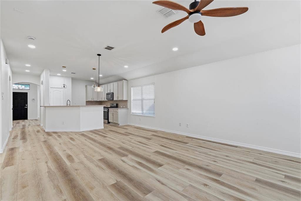 10709 Nantucket Drive, Rowlett, TX 75089 Open-concept living area featuring wood-finish flooring, recessed lighting, a modern ceiling fan, and a kitchen island with pendant lighting