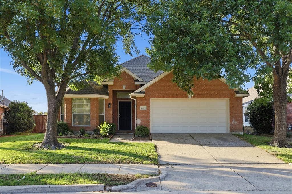 10709 Nantucket Drive, Rowlett, TX 75089 Brick exterior with an attached two-car garage, mature trees, and a concrete driveway