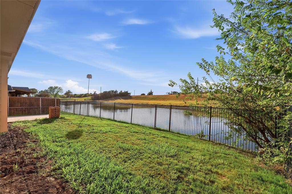 10709 Nantucket Drive, Rowlett, TX 75089 Expansive backyard featuring a manicured lawn, a black metal fence, and a water feature