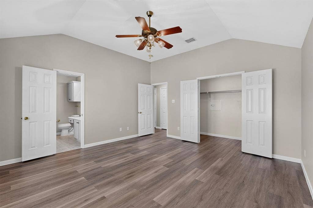 Vaulted ceilings with a ceiling fan, wood-finish flooring, and a walk-in closet with bi-fold doors