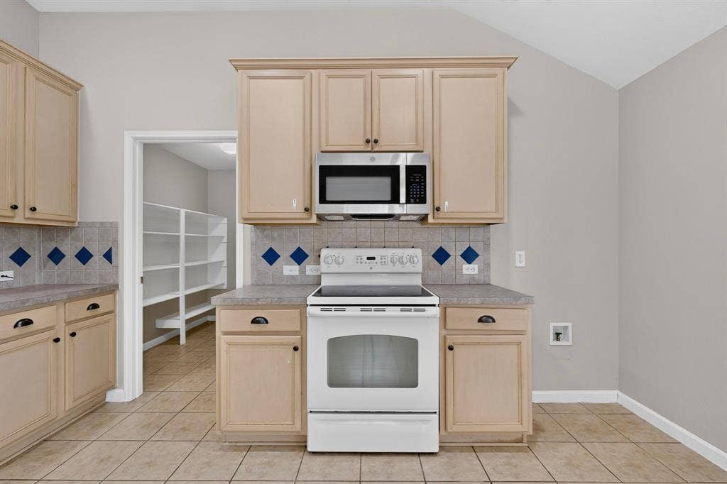 Kitchen featuring light-toned cabinetry, tile flooring, and a stainless steel microwave