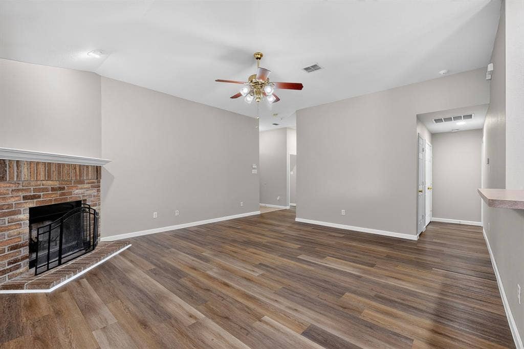 Spacious room featuring wood-finish flooring, a brick fireplace with a hearth, a ceiling fan, and recessed lighting