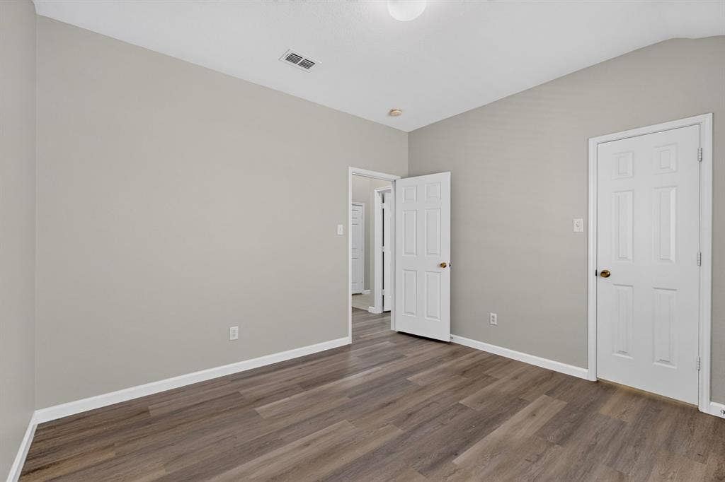 Wood-finish flooring, light gray wall paint, white trim, and white paneled doors