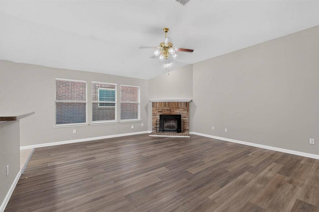 Vaulted ceilings, wood-finish flooring, brick fireplace, and multiple windows