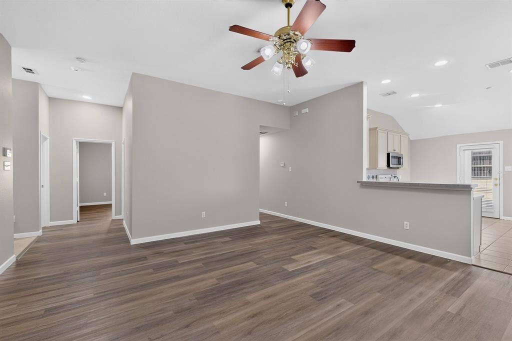Wood-finish flooring throughout, vaulted ceiling, recessed lighting, and a ceiling fan with integrated lighting