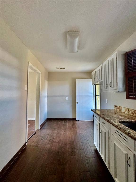 8018 S Reno Court, Dallas, TX 75217 Galley kitchen with wood-finish flooring, white cabinetry, and granite countertops