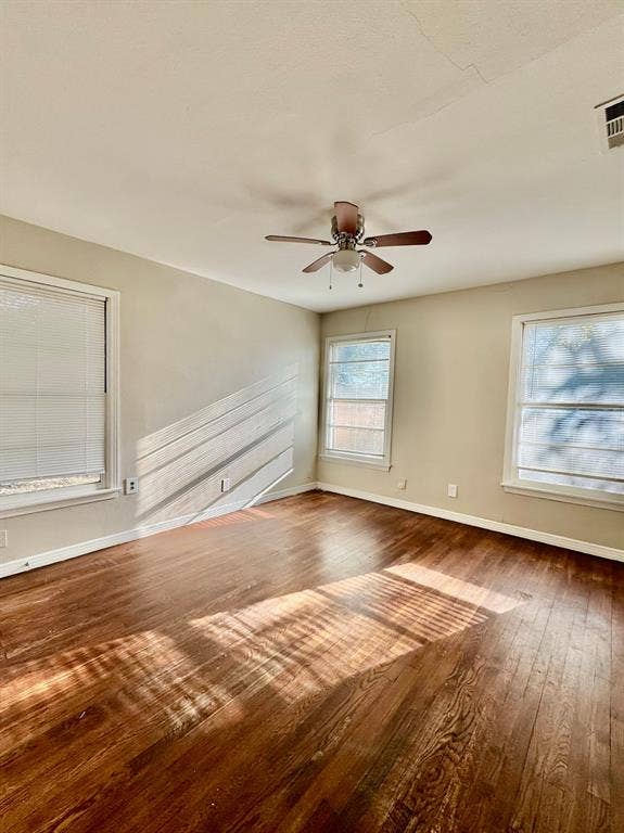 8018 S Reno Court, Dallas, TX 75217 Spacious room featuring wood-finish flooring and multiple windows for natural light