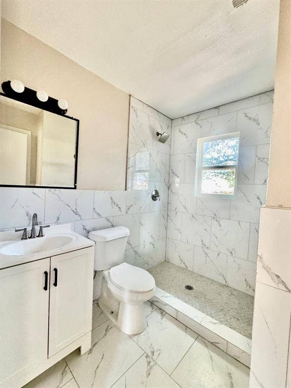 8018 S Reno Court, Dallas, TX 75217 Bathroom featuring a walk-in shower with tile surround, a single vanity with a rectangular sink, and a framed mirror with overhead lighting