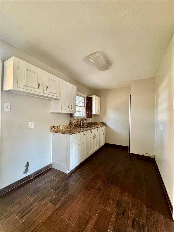 8018 S Reno Court, Dallas, TX 75217 Wood-finish flooring throughout, white cabinetry, dark stone countertops, stainless steel sink, and ample storage