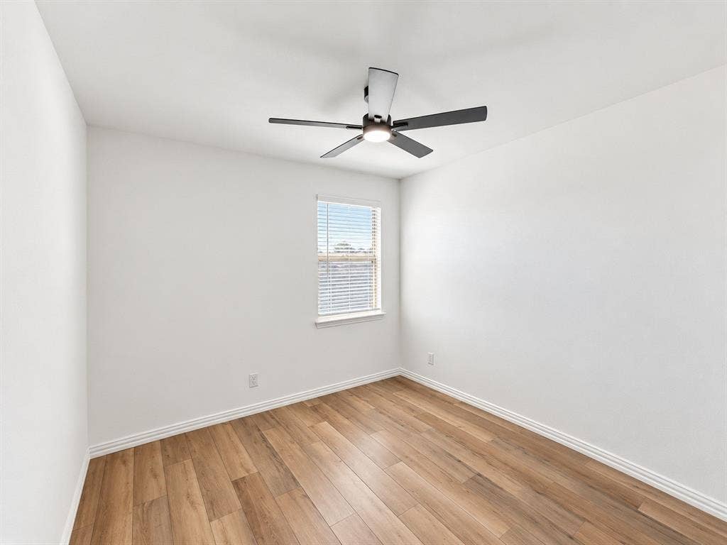 1605 River Crossing Drive, Anna, TX 75409 Wood-finish flooring with crisp white walls, a single window with blinds, and a ceiling fan with integrated lighting