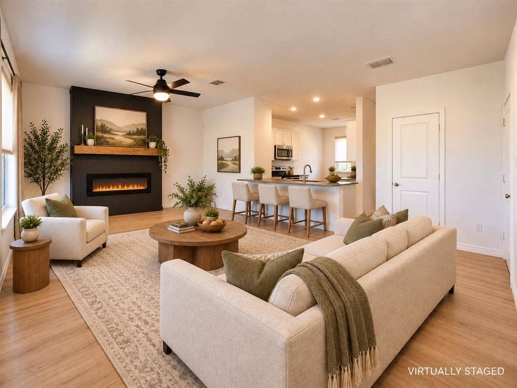 1605 River Crossing Drive, Anna, TX 75409 Open-concept living area with wood-finish flooring, a contemporary ceiling fan, and a built-in electric fireplace featuring a wood mantel
