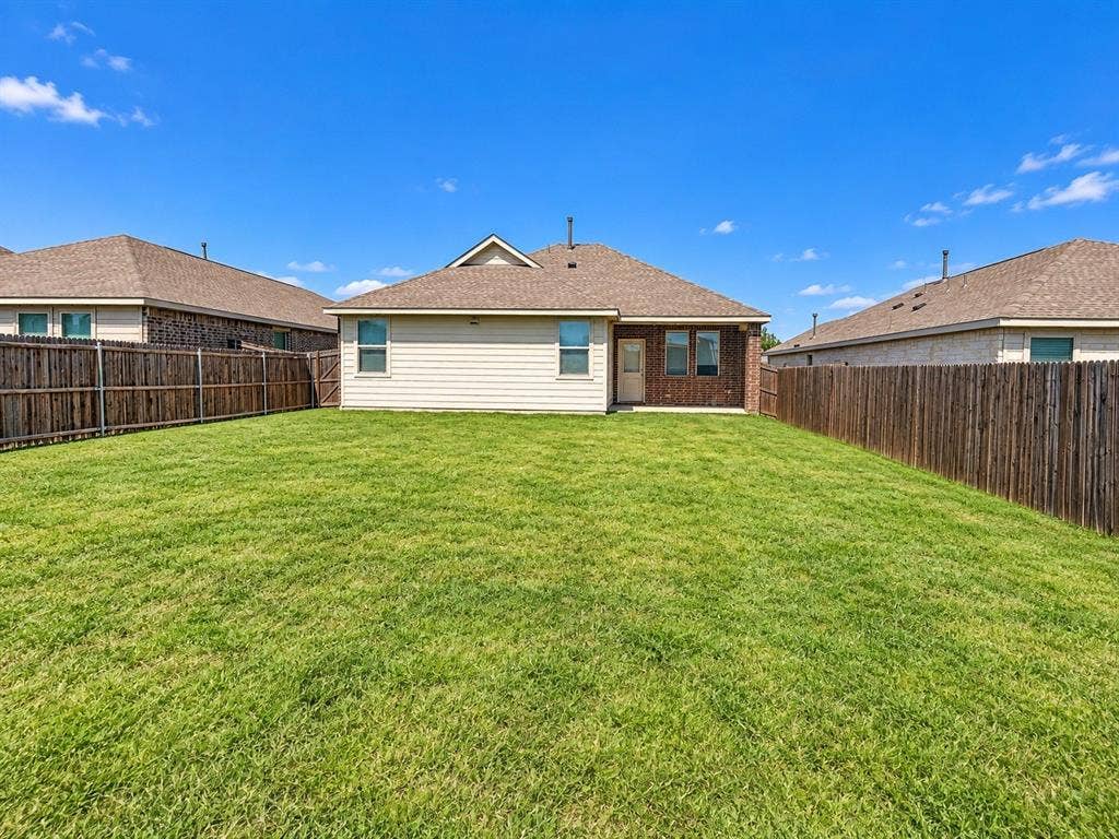 1605 River Crossing Drive, Anna, TX 75409 Expansive grassy yard with wood fencing, brick and siding exterior, and a rear entry door