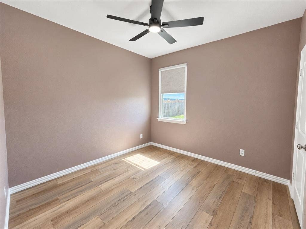 1605 River Crossing Drive, Anna, TX 75409 Neutral-toned walls, wood-finish flooring, ceiling fan, and a single window with a roller shade