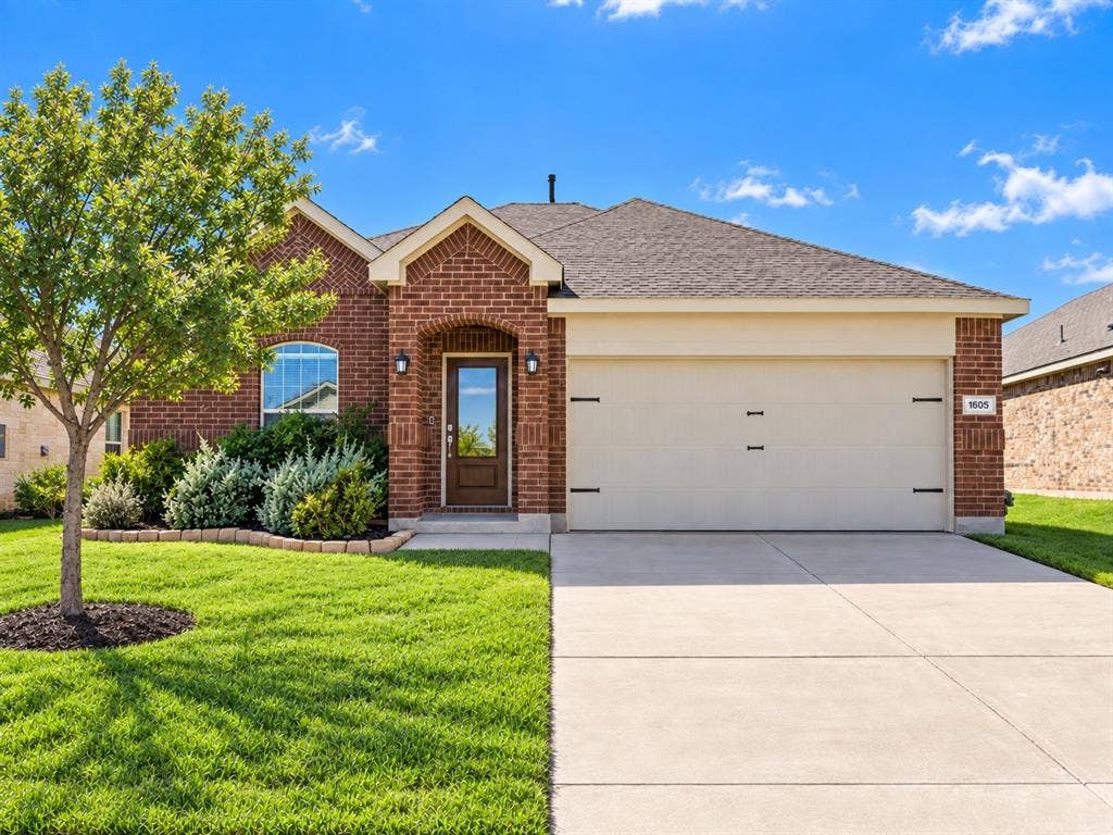 1605 River Crossing Drive, Anna, TX 75409 Brick exterior with an arched entry, mature landscaping, and an attached two-car garage