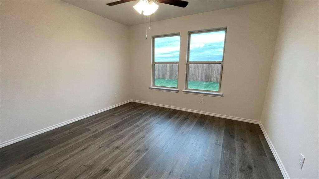409 White Willow Drive, Nevada, TX 75173 Wood-finish flooring with white trim, two windows, and a ceiling fan