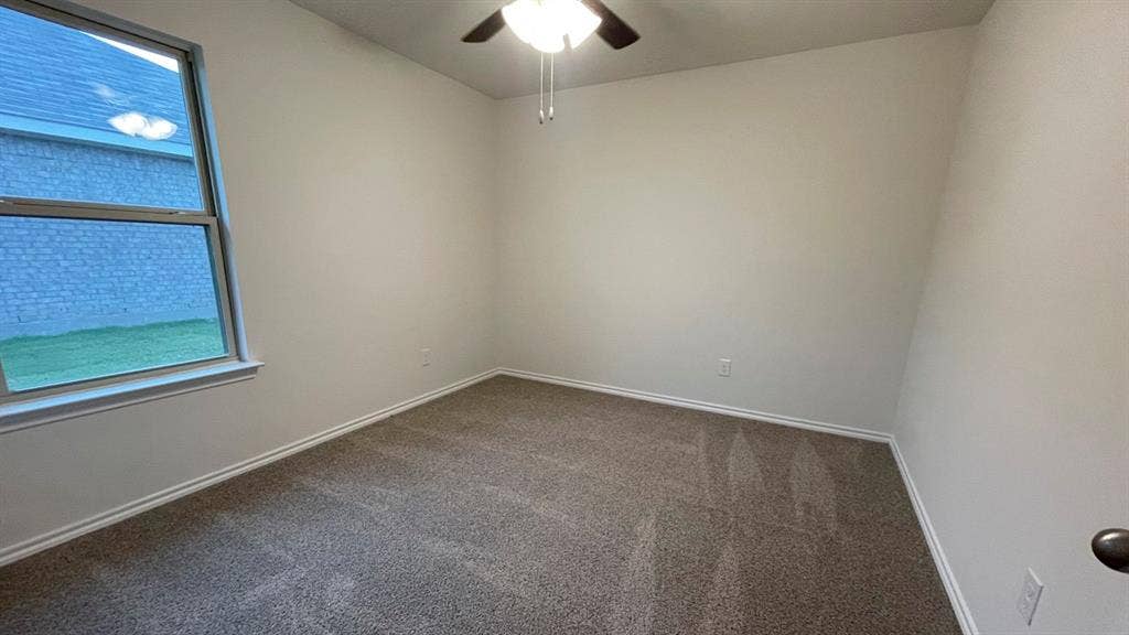 409 White Willow Drive, Nevada, TX 75173 Neutral wall paint with textured carpeting, a ceiling fan with integrated lighting, and a double-paned window