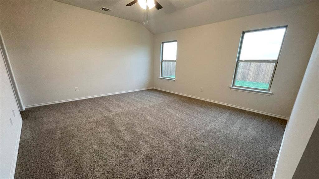 409 White Willow Drive, Nevada, TX 75173 Vaulted ceiling, ceiling fan with light fixture, two windows, wall-to-wall carpeting, and neutral paint palette