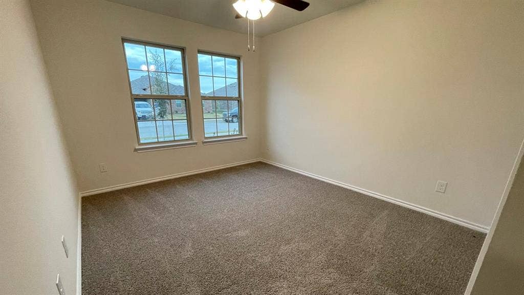 409 White Willow Drive, Nevada, TX 75173 Plush carpet flooring, neutral wall paint, two large windows, and a ceiling fan