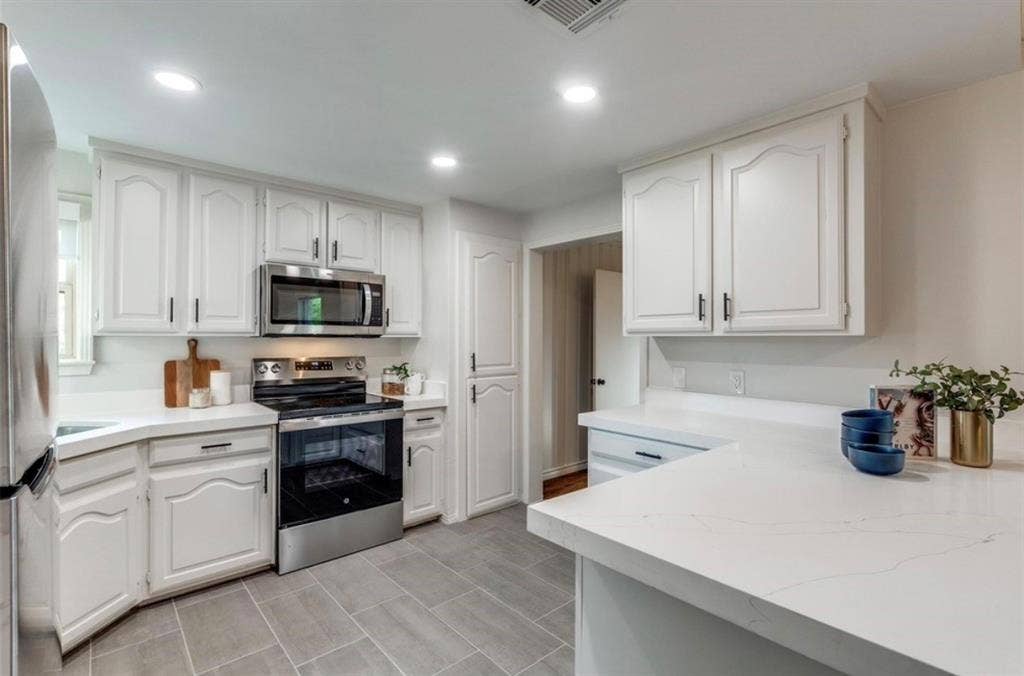 1323 Engle Avenue, Dallas, TX 75224 White cabinetry with black hardware, stainless steel appliances, solid surface countertops, recessed lighting, and tile flooring