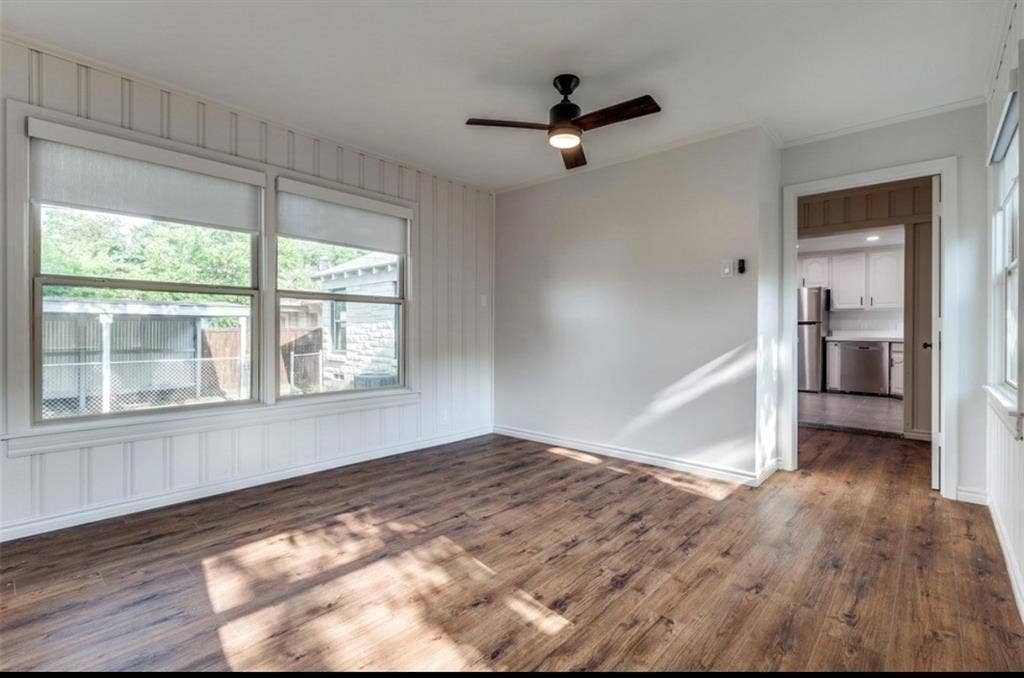 1323 Engle Avenue, Dallas, TX 75224 Wood-finish flooring, white paneled walls, a ceiling fan with integrated lighting, and multiple windows with roller shades