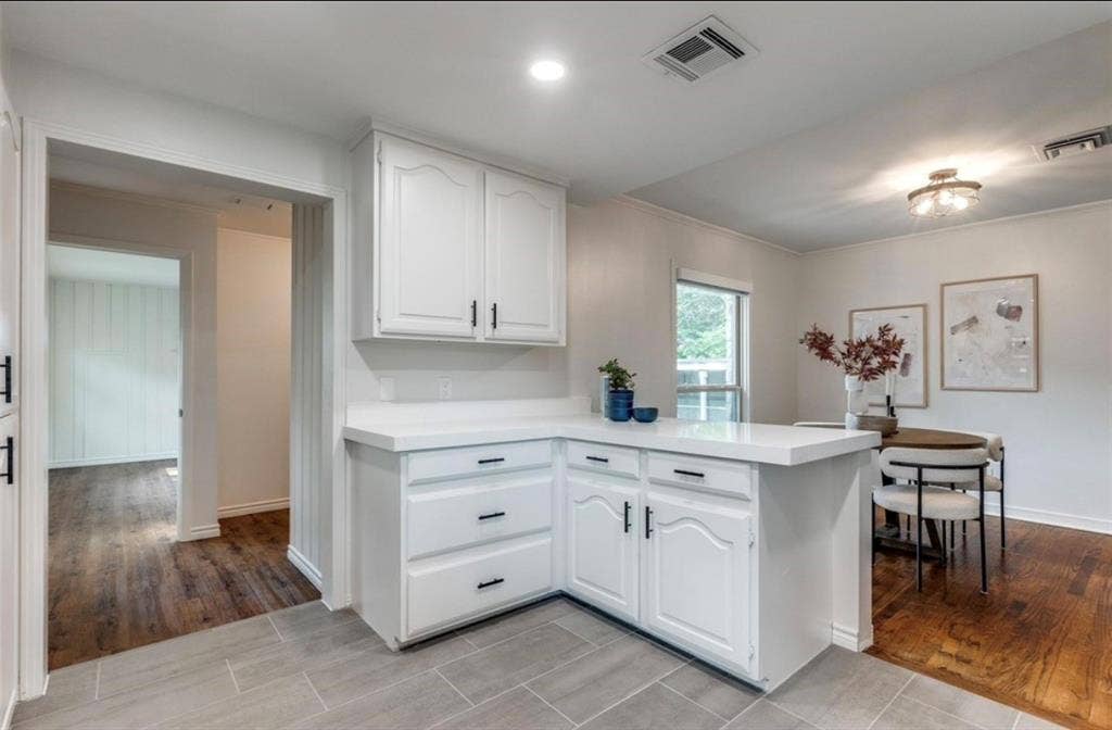 1323 Engle Avenue, Dallas, TX 75224 White cabinetry with black hardware, light-toned countertops, tile flooring, wood-finish flooring, and a window providing natural light
