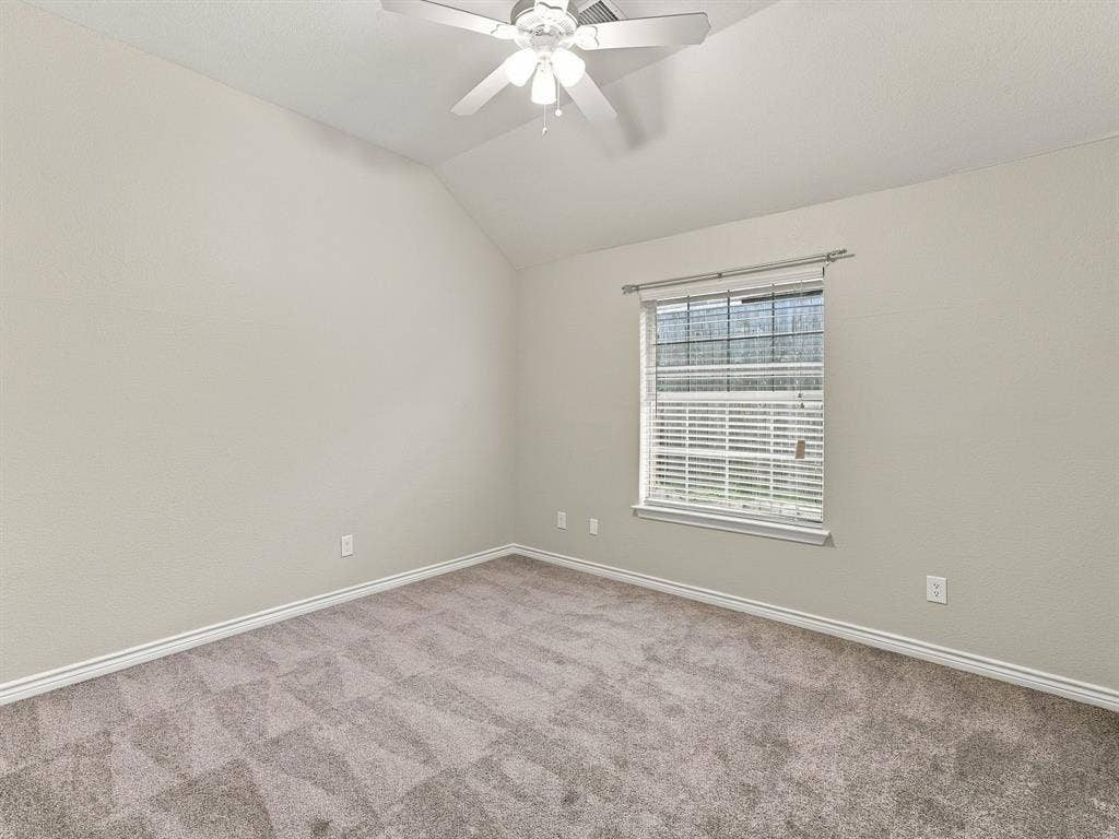 Vaulted ceiling with a ceiling fan, window with blinds, and carpet flooring