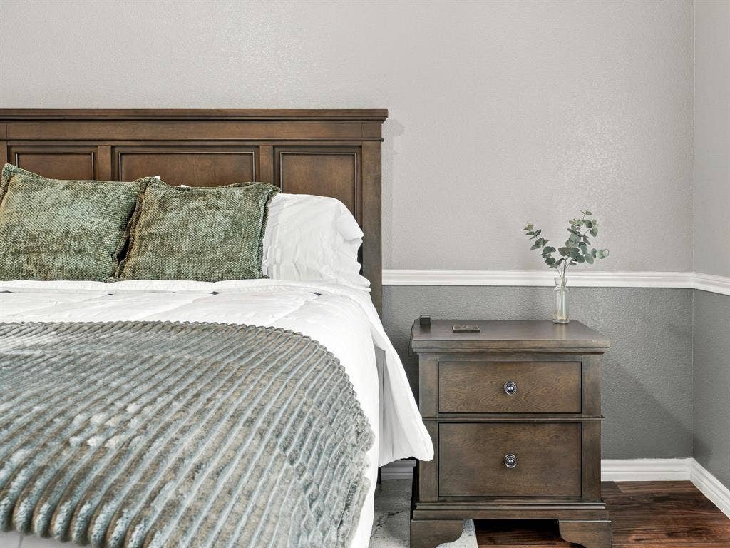 Paneled wood headboard, two-drawer nightstand with dark hardware, two-tone wall treatment, and white crown molding
