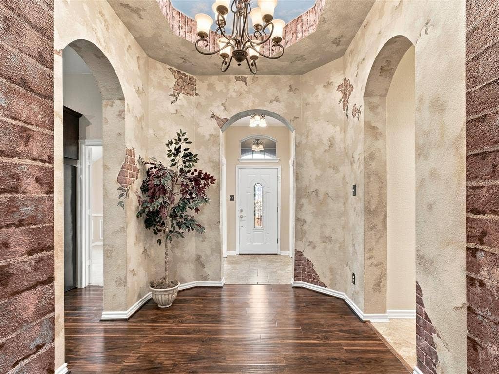 Wood-finish flooring with arched doorways, a coffered ceiling, and a decorative chandelier