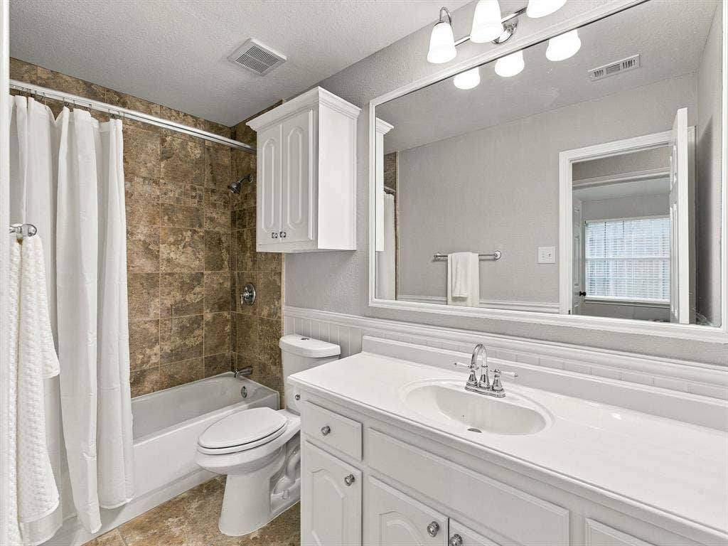Bathroom featuring a white vanity with an integrated sink, polished chrome faucet, and a large wall-mounted mirror