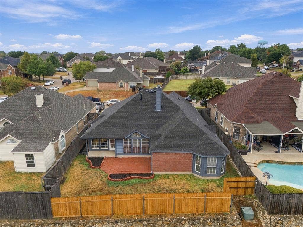 Backyard featuring a red brick patio, contrasting blue siding, and a wood privacy fence