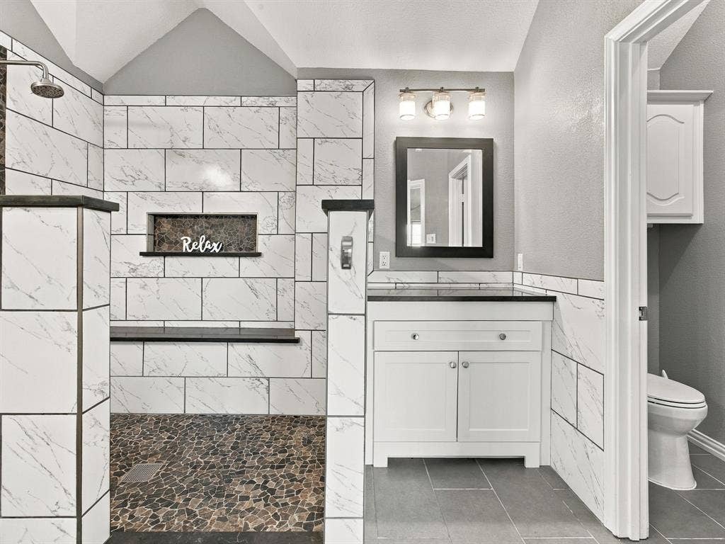Walk-in shower with pebble tile flooring and a built-in bench