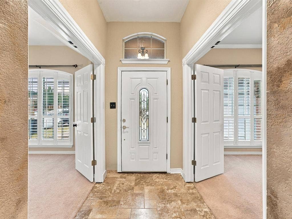 Entryway featuring a decorative glass front door, transom window, and tiled flooring