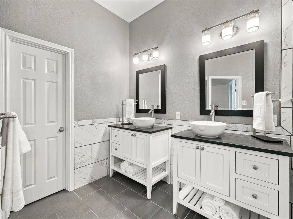 Dual vanity setup with white shaker cabinetry, dark countertops, and vessel sinks