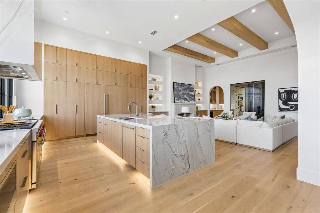 Kitchen featuring modern built-in cabinets, White oak floors, Wolf & SubZero appliances, light stone countertops, and recessed lighting