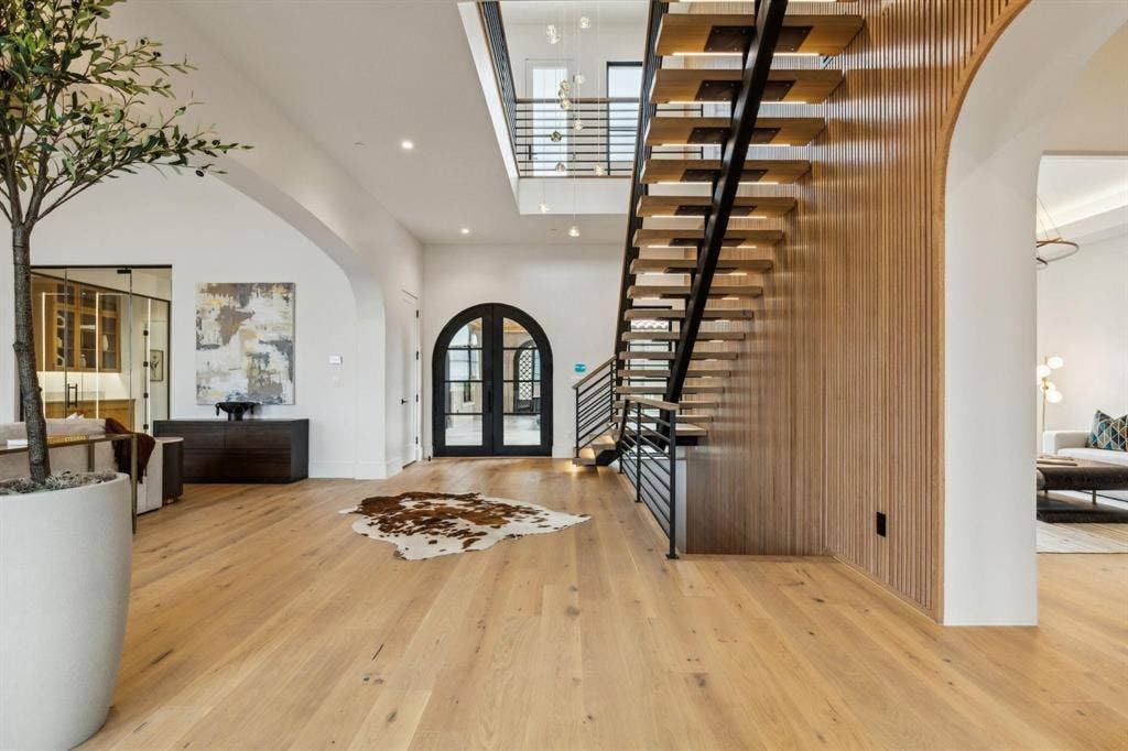 Foyer featuring arched walkways, a high ceiling, light wood-style flooring, recessed lighting, and stairs