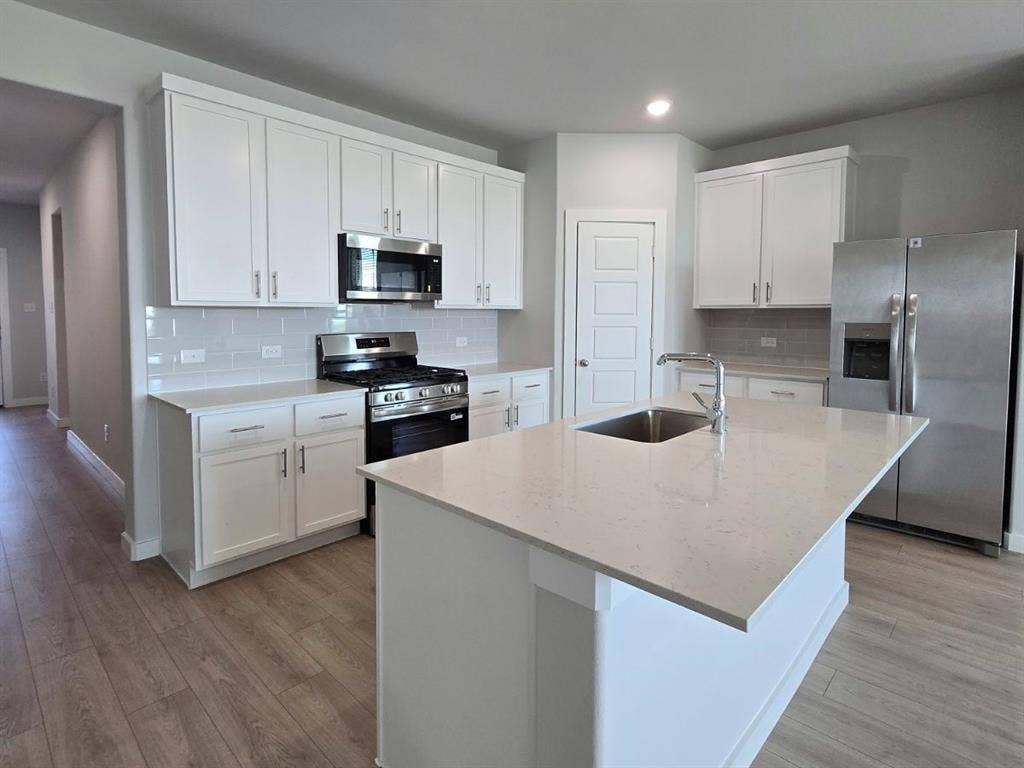 841 Rockcloud Drive, Fort Worth, TX 76052 Kitchen featuring white cabinetry, stainless steel appliances, light-toned countertops, subway tile backsplash, and wood-finish flooring