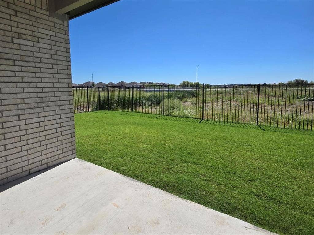 841 Rockcloud Drive, Fort Worth, TX 76052 Manicured lawn with a concrete patio, brick exterior, and black metal fencing