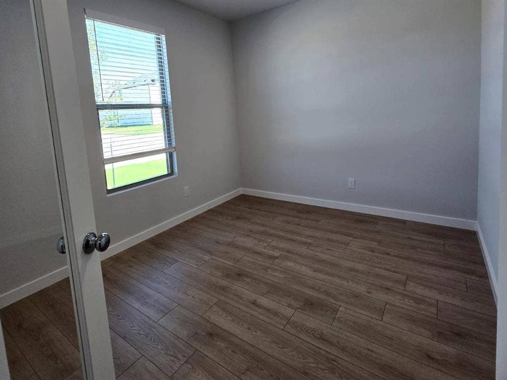 841 Rockcloud Drive, Fort Worth, TX 76052 Wood-finish flooring, white wall paint, window with blinds, white trim, and a chrome doorknob