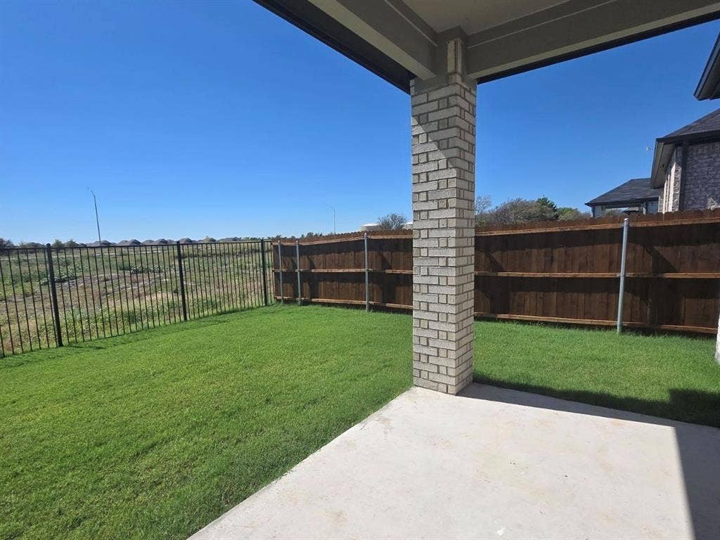 841 Rockcloud Drive, Fort Worth, TX 76052 Expansive backyard featuring a concrete patio, brick column support, and a wood privacy fence