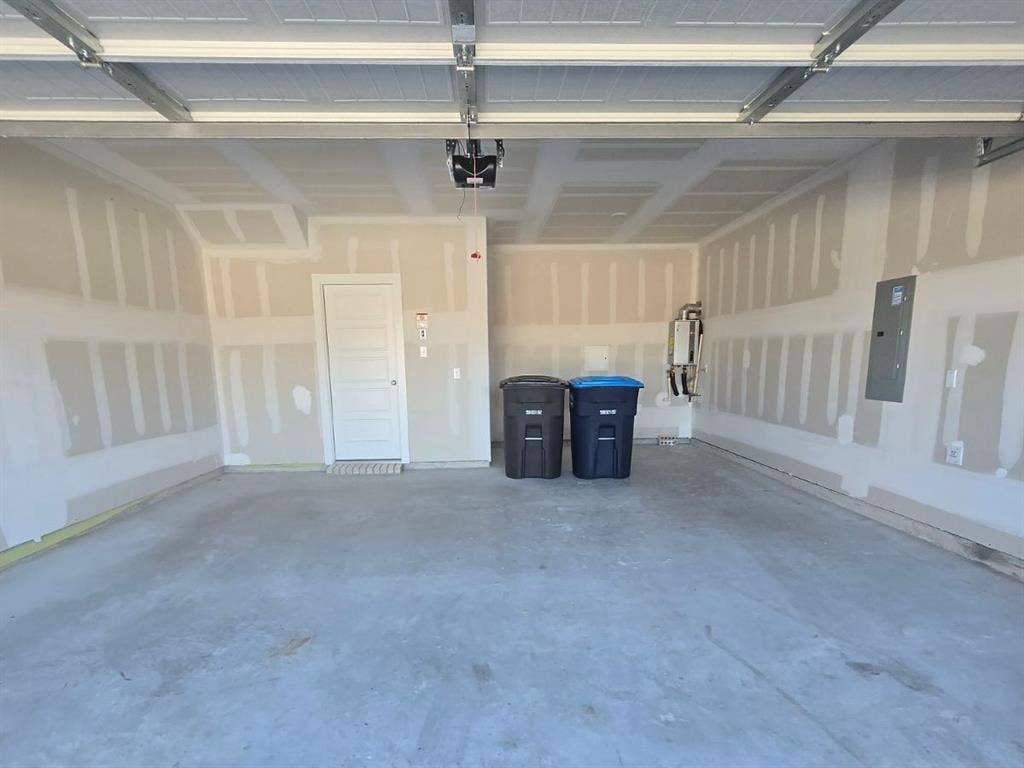 841 Rockcloud Drive, Fort Worth, TX 76052 Interior garage space featuring a concrete floor, an overhead garage door mechanism, and a side-entry door