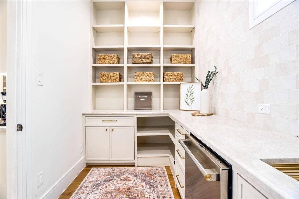 12007 Quincy Lane, Dallas, TX 75230 Built-in shelving, white cabinetry with gold-tone hardware, light-toned countertop, and a tiled backsplash