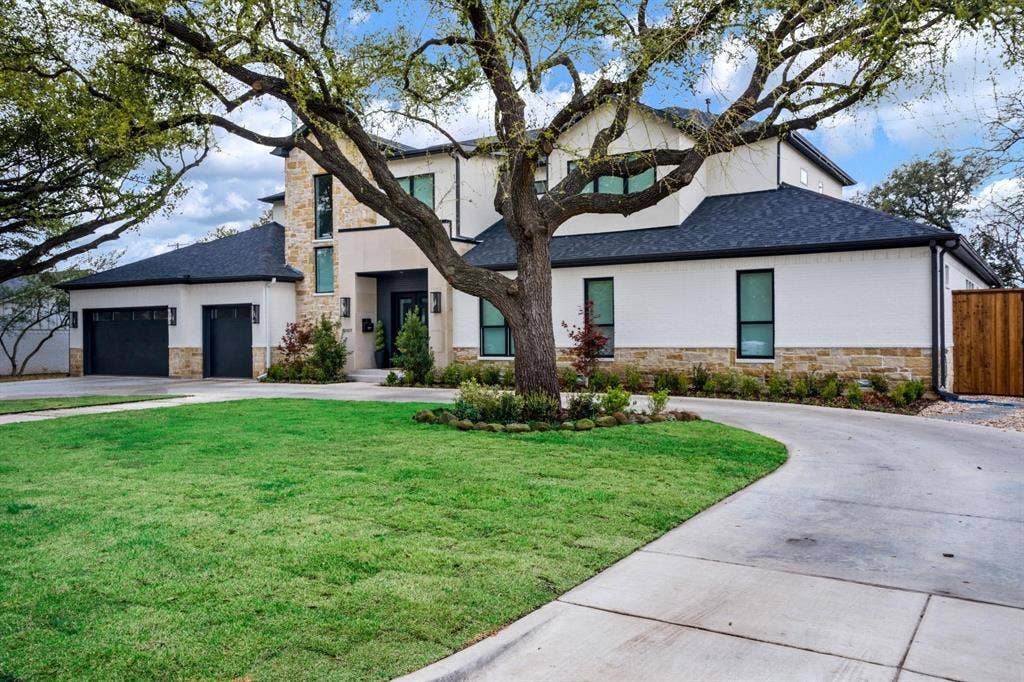 12007 Quincy Lane, Dallas, TX 75230 Modern exterior featuring a prominent stone facade, white stucco, dark-framed windows, a black shingle roof, and a concrete driveway
