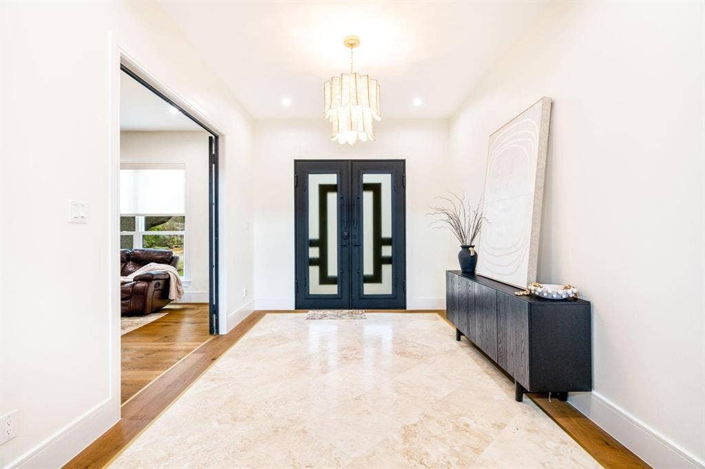 12007 Quincy Lane, Dallas, TX 75230 Entryway featuring a decorative chandelier, recessed lighting, double entry doors with geometric glass inserts, and stone tile flooring with a wood-finish border