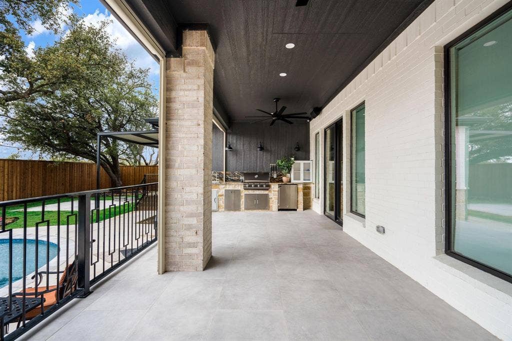 12007 Quincy Lane, Dallas, TX 75230 Expansive covered patio with recessed lighting, an outdoor kitchen featuring stainless steel appliances, a ceiling fan, and a light brick support column