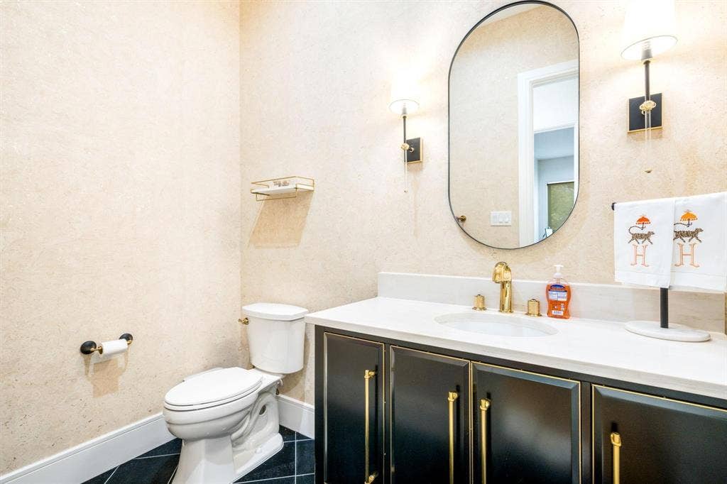 12007 Quincy Lane, Dallas, TX 75230 White countertop with an undermount sink, gold-finish faucet, and black vanity with gold-tone hardware