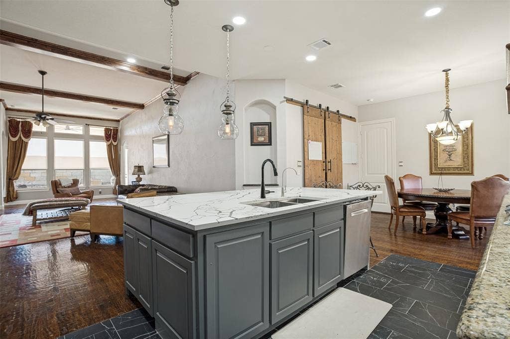 1250 Packsaddle Trail, Prosper, TX 75078 Kitchen island with a white stone countertop, dual basin sink, and gray cabinetry