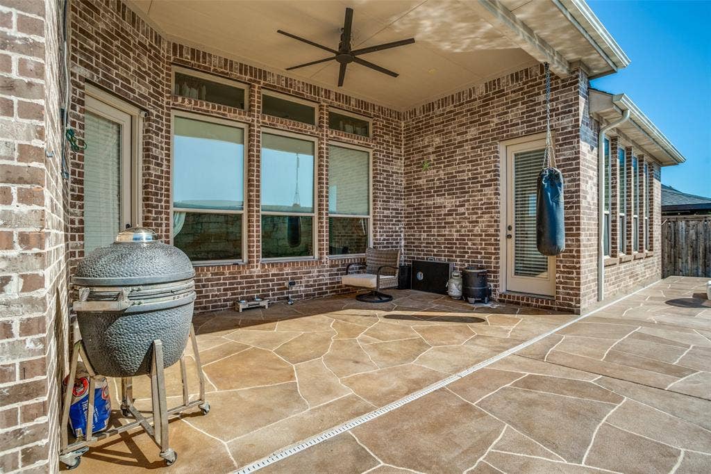 1250 Packsaddle Trail, Prosper, TX 75078 Covered patio featuring brick construction, a ceiling fan, multiple windows, and flagstone-patterned concrete flooring