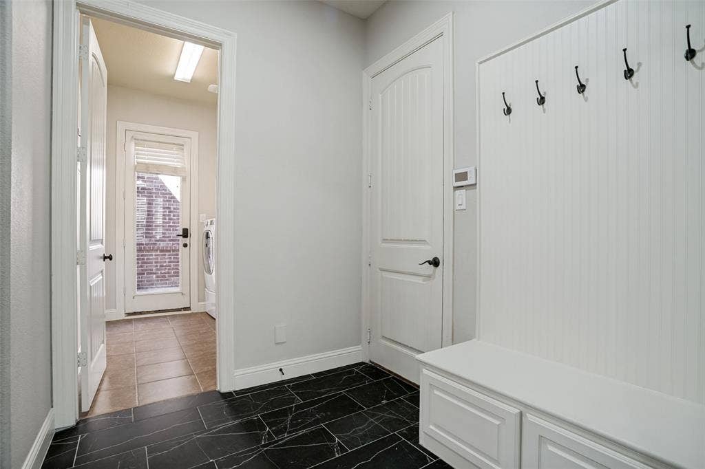 1250 Packsaddle Trail, Prosper, TX 75078 Built-in bench with storage, black tile flooring, white beadboard wall, and a full-light exterior door